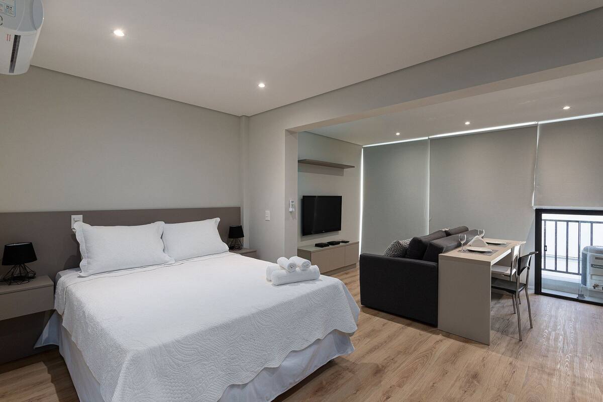 Ein modernes Hotelzimmer mit einem großen Bett, einem Schreibtisch, einer Couch und einem Fernseher.