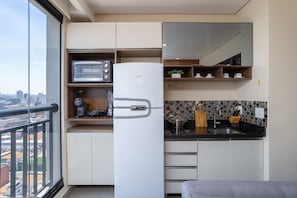 A compact kitchen with a microwave, refrigerator, and sink.