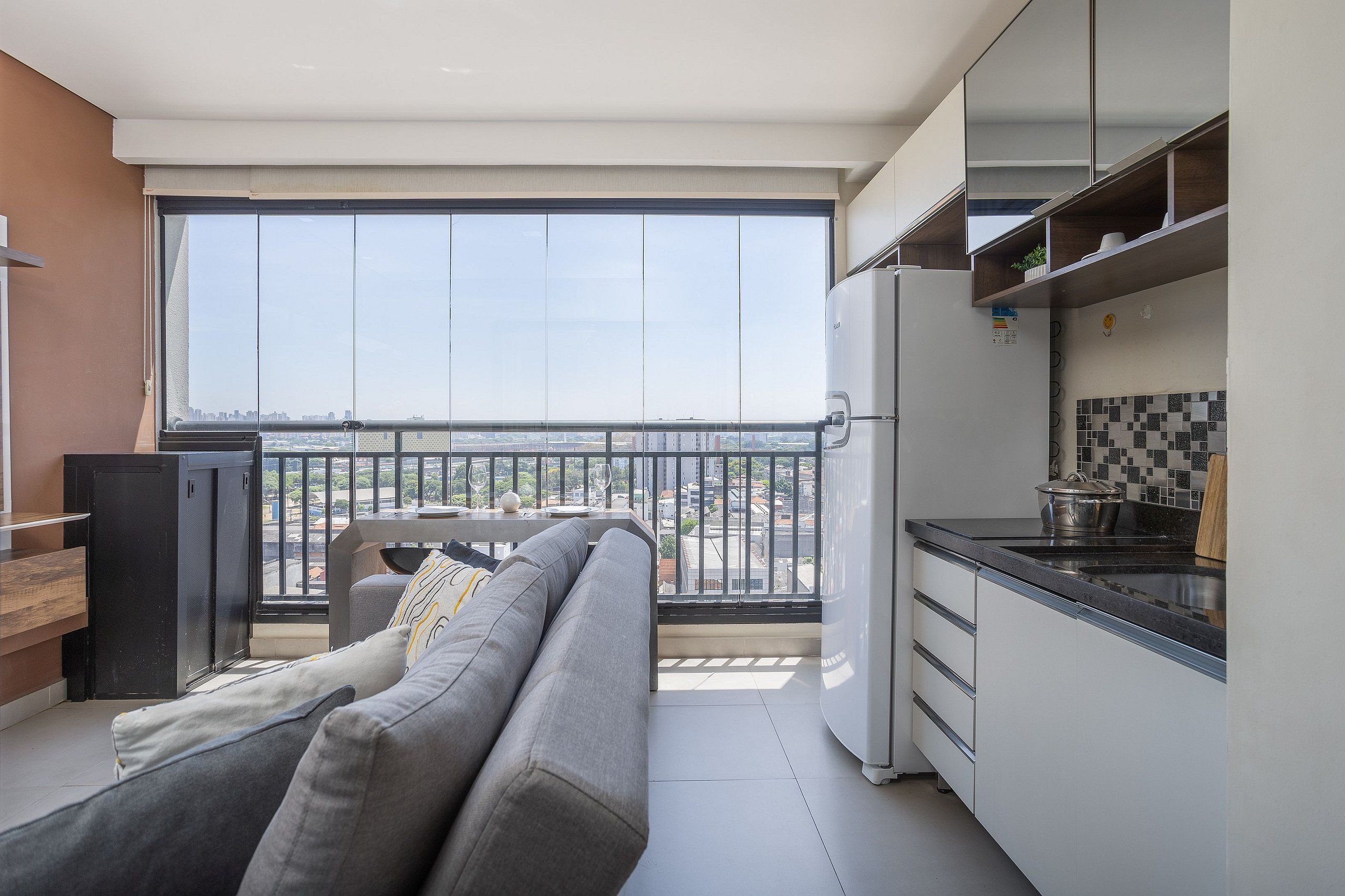 Um apartamento moderno com varanda, sofá, cozinha e vista para a cidade.