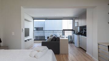 Une chambre d’hôtel moderne dotée d’un grand lit, d’un canapé, d’un petit coin cuisine et d’un balcon avec vue.