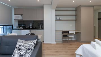 Un appartement moderne comprenant une cuisine, un coin repas et un salon avec un canapé et un fauteuil.