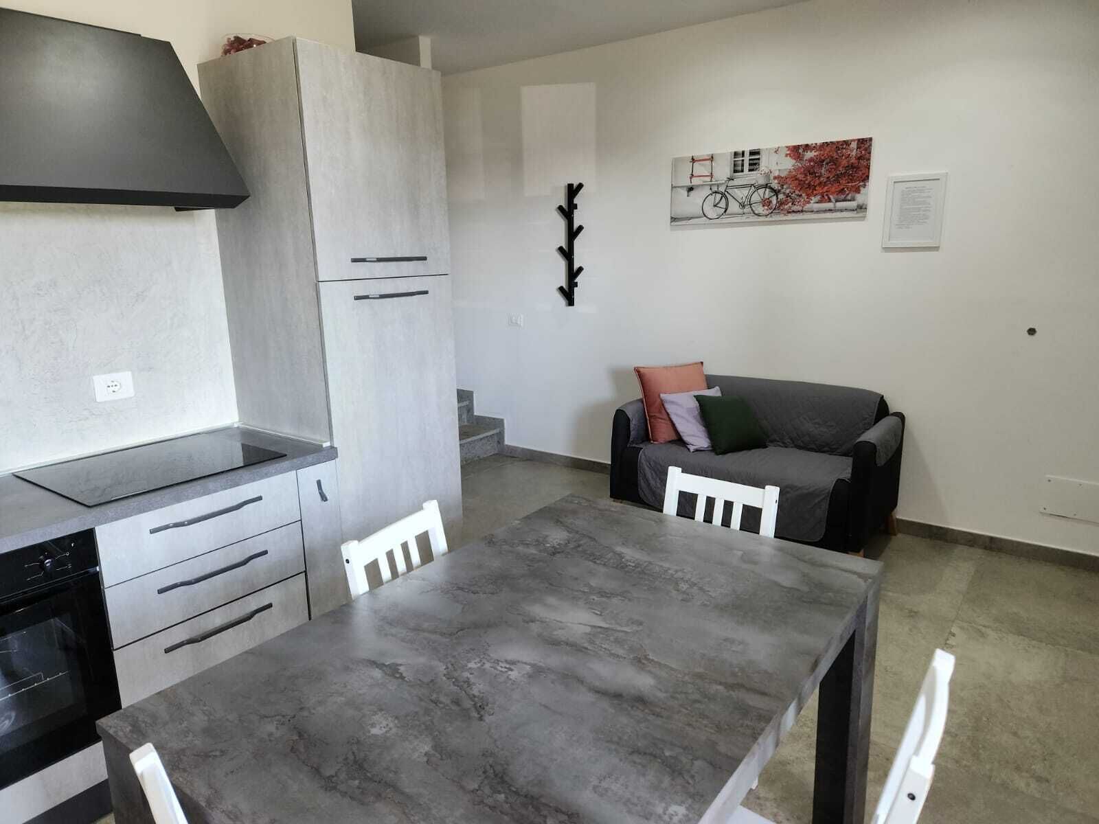 A modern kitchen with grey cabinets, a black stove, and a dining table with chairs.