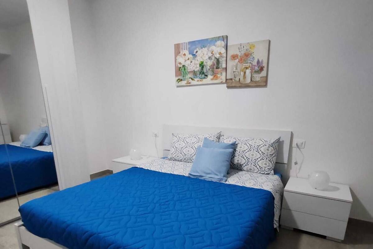 Ein Schlafzimmer mit einem Bett, zwei Nachttischen und einem Spiegel.