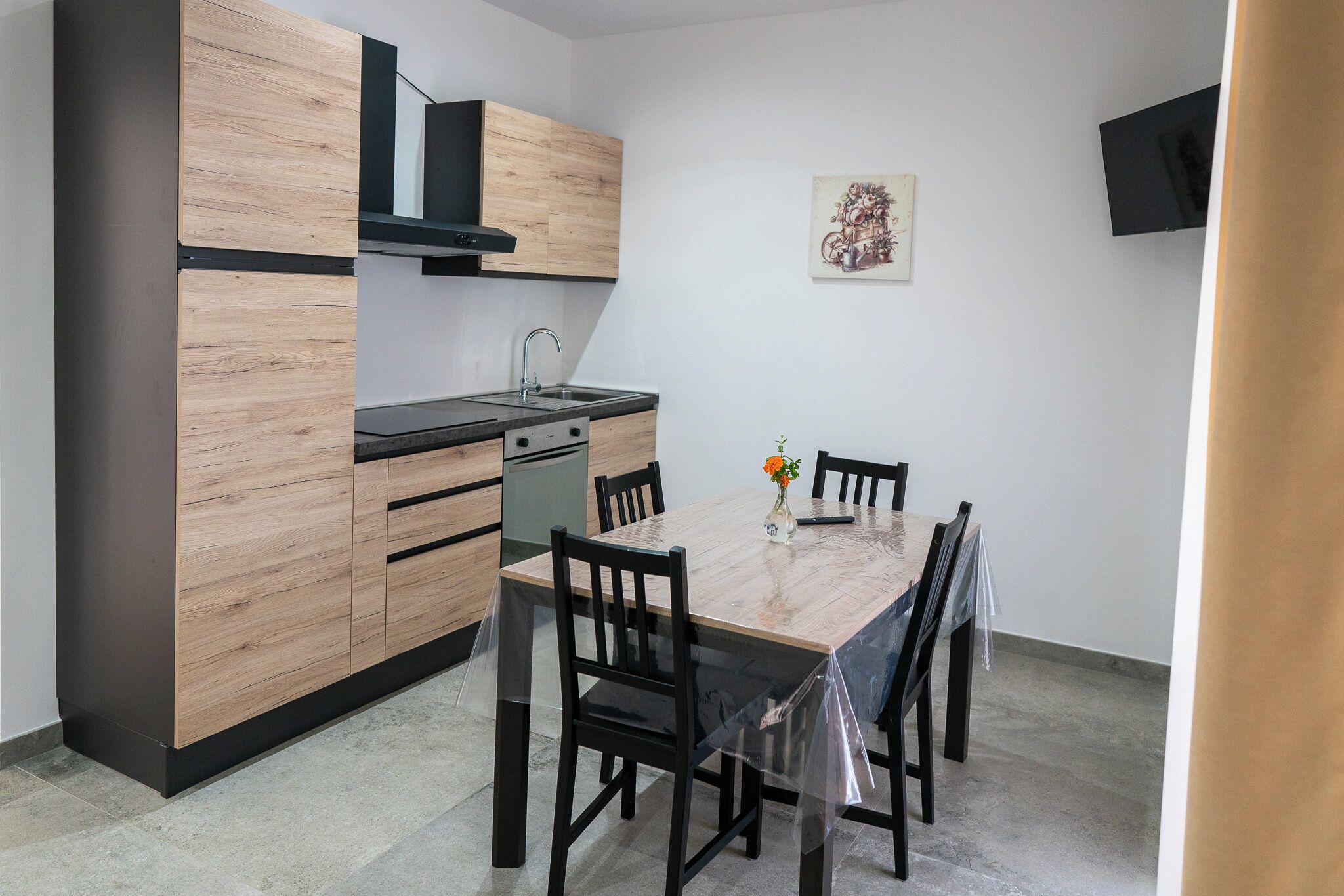 A compact kitchen with wooden cabinets, a black countertop, and a dining table with chairs.