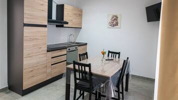 A compact kitchen with wooden cabinets, a black countertop, and a dining table with chairs.
