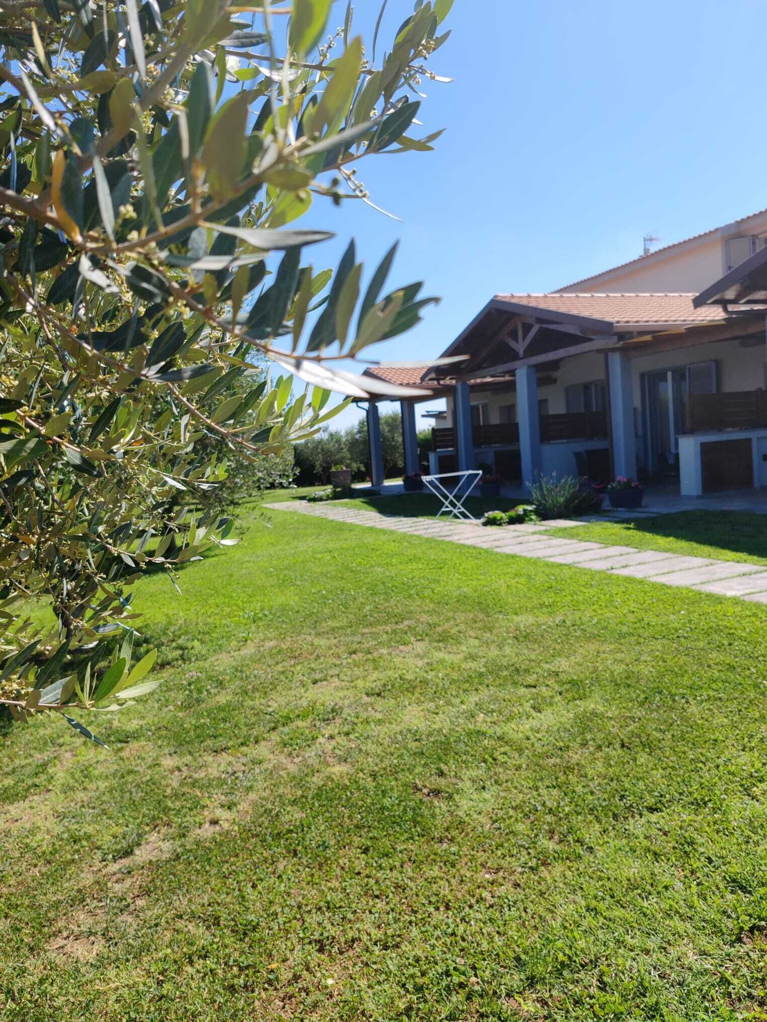 Un césped bien cuidado con un patio, una zona de estar cubierta y un edificio con tejado de baldosas.