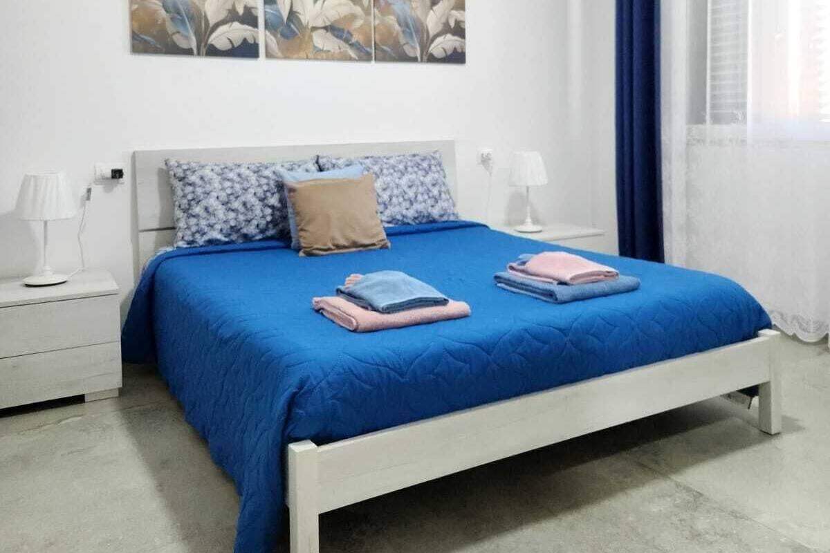Ein Schlafzimmer mit einem weißen Bett, blauer Bettwäsche und zwei an der Wand hängenden Bildern.