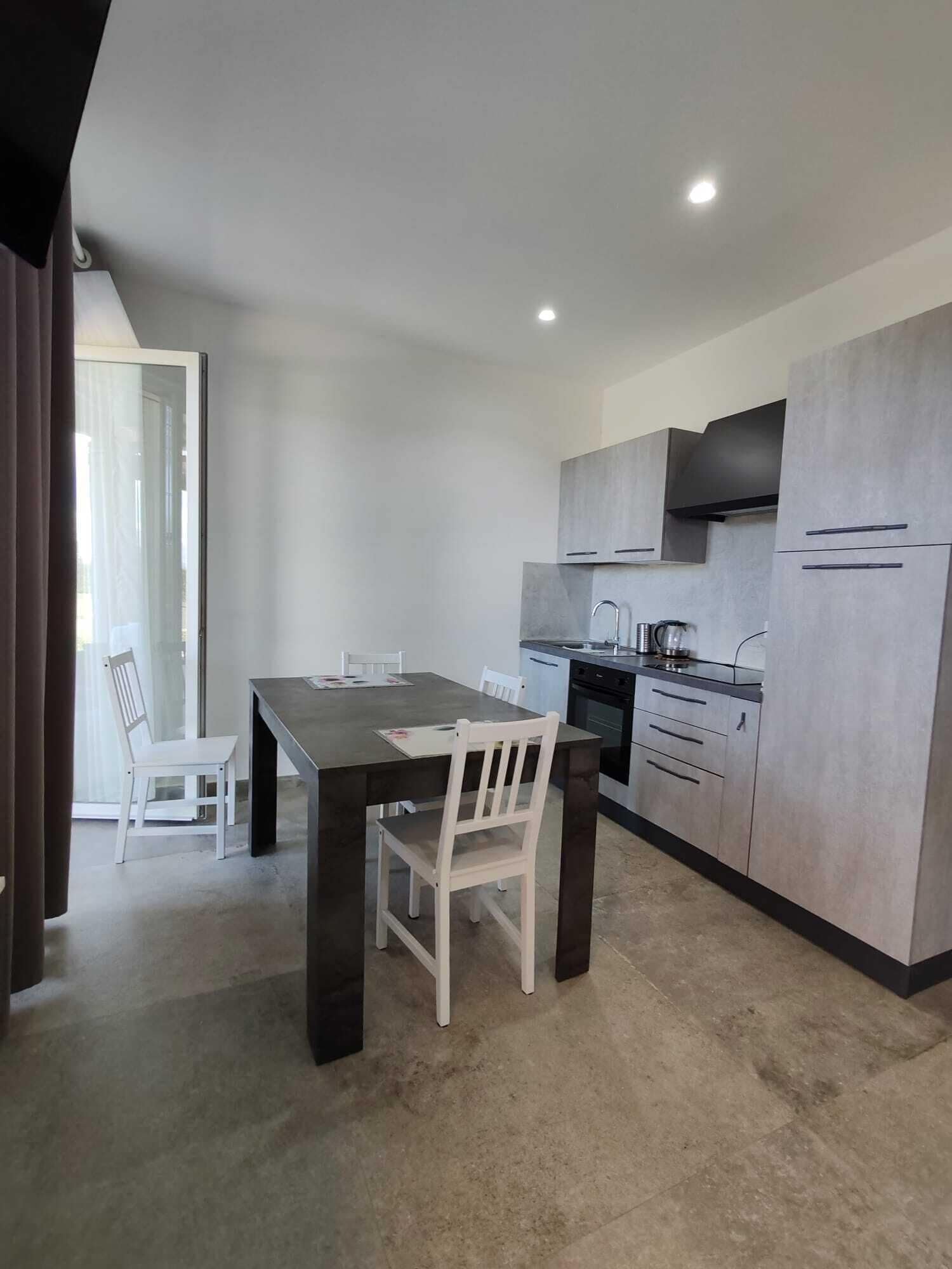 A modern kitchen with grey cabinets, a dark countertop, and a stainless steel range hood.