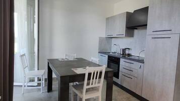 A modern kitchen with grey cabinets, a dark countertop, and a stainless steel range hood.