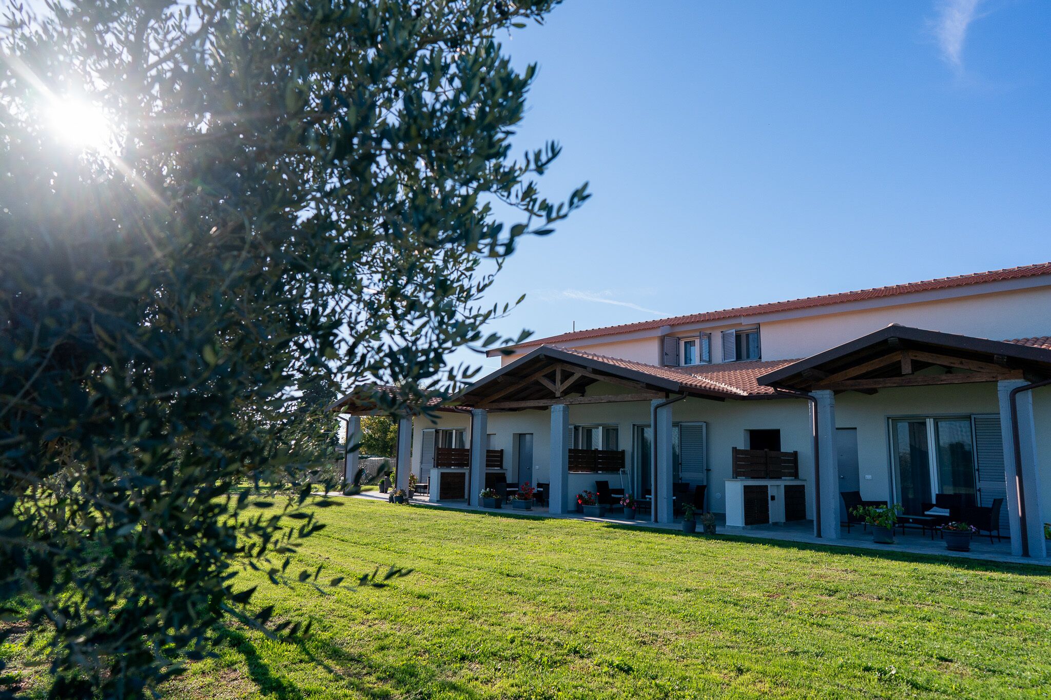A two-story building with a tiled roof and a covered patio area.