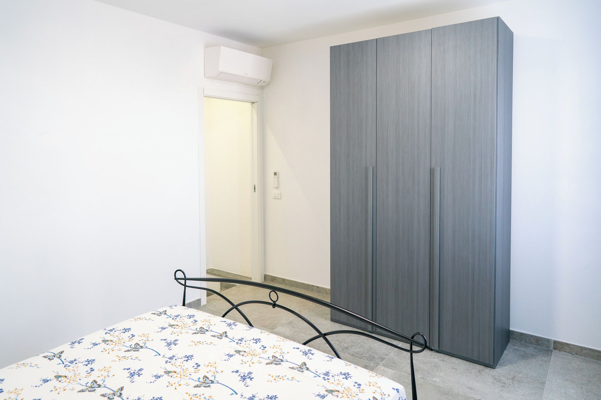 A bedroom with a bed, a wardrobe, and a door leading to another room.