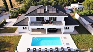 Ett tvåvåningshus med en swimmingpool och en täckt uteplats.