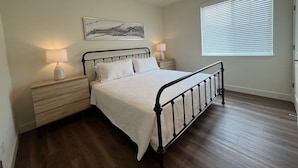 A bedroom with a bed, nightstands, a lamp, a painting, and a window with blinds. - Lakeview Retreat: Golf, Fish, & Explore the Trails (Sparks)