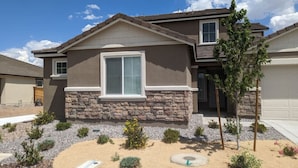 A two-story house with a stone facade, a large window, and a landscaped front yard with various plants and a small tree. - Lakeview Retreat: Golf, Fish, & Explore the Trails (Sparks)