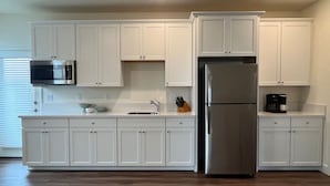 A modern kitchen with white cabinetry, a stainless steel refrigerator, and a microwave. - Lakeview Retreat: Golf, Fish, & Explore the Trails (Sparks)