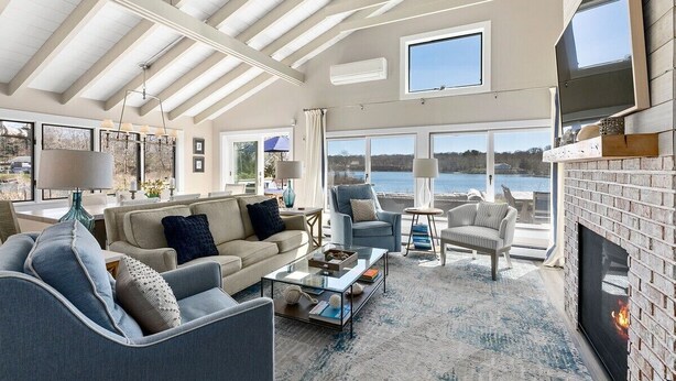 Un salón amplio con chimenea, ventanas grandes y vista al agua.