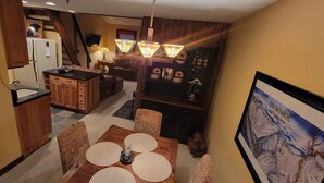 A cozy interior with a wooden dining table set for four, a kitchen area with wooden cabinets, and a living space with a sofa and a Christmas tree. - Cozy Loft nestled atop of Snowshoe (Snowshoe)