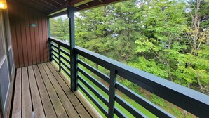 A wooden deck with a railing overlooking a forested area. - Cozy Loft nestled atop of Snowshoe (Snowshoe)