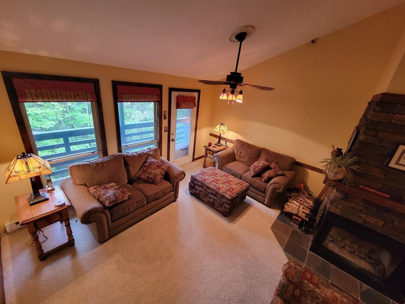 A cozy living room with two sofas, a coffee table, a fireplace, and a ceiling fan.