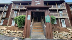 A two-story building with a sign reading "Monta in Crest" and a dolphin logo. There are signs indicating unit numbers and a "No Parking Do Not Block Stairway" sign. - Cozy Loft nestled atop of Snowshoe (Snowshoe)