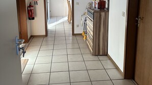 A hallway with a fire extinguisher, a door with a handle, a wall-mounted sign, and a tiled floor. - Vacation apartment Haren /Ems for up to 6 people  (Haren (Ems))