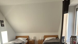 A bedroom with two beds, a window, a radiator, and a small rug. - Vacation apartment Haren /Ems for up to 6 people  (Haren (Ems))