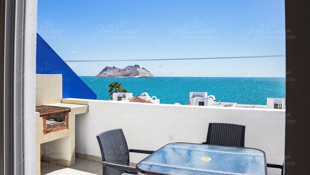 A balcony with a view of the sea and a rocky island.