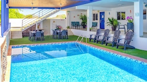 A swimming pool with a tiled deck, outdoor seating, and a staircase leading to an upper level.