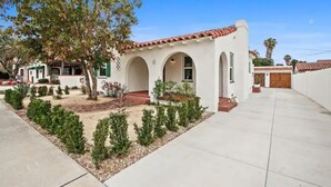 A single-story building with a red-tiled roof, white walls, and arched doorways. - 1920's Spanish Revival Home (Tustin)