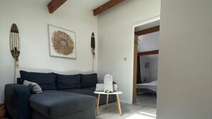 Uma sala de estar moderna com um sofá seccional cinzento, uma pequena mesa branca e um claraboia no teto.