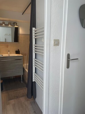 Un baño con lavamanos, espejo, toallero y una puerta con manija.
