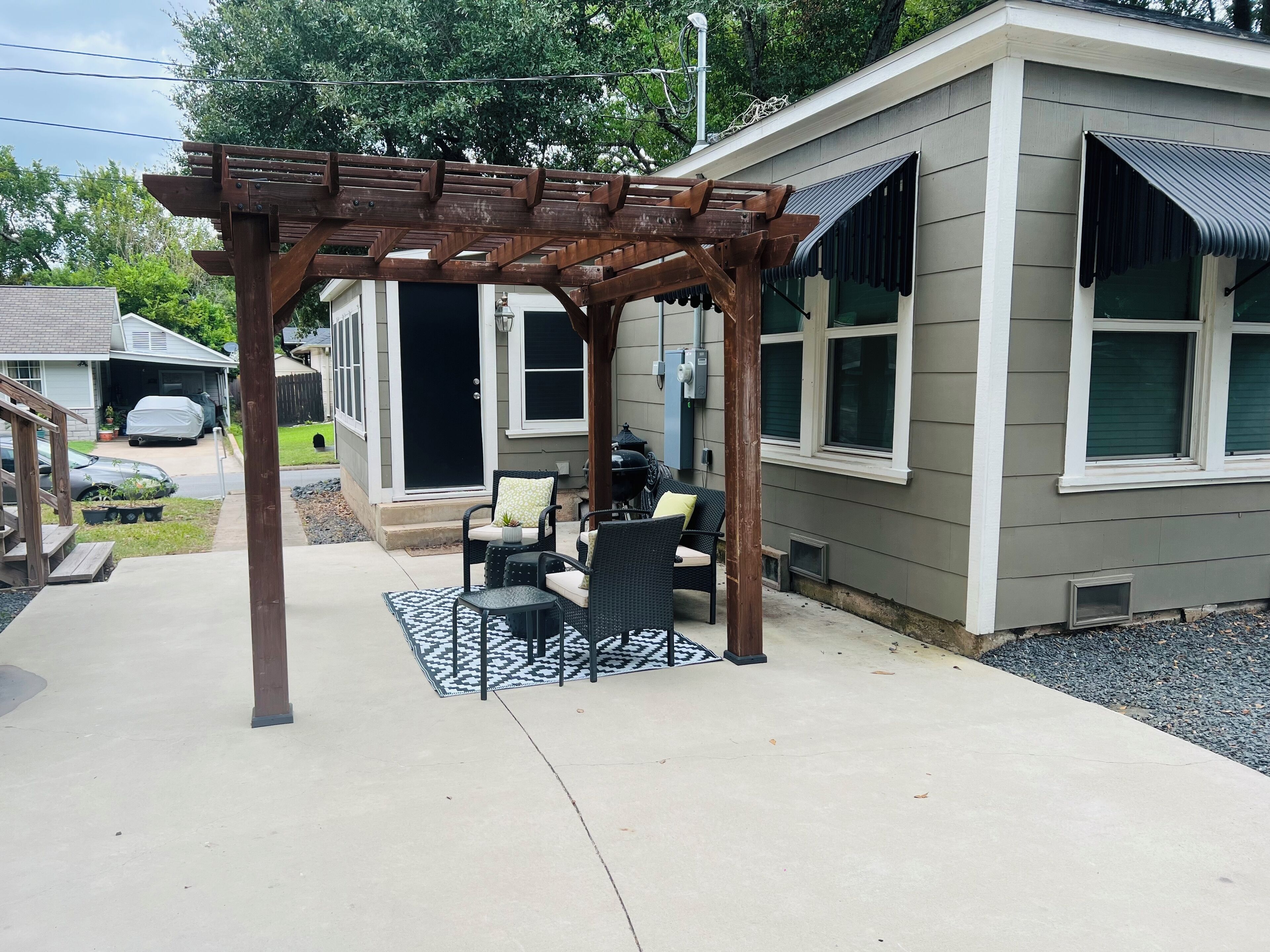 A covered patio area with outdoor furniture, a pergola, and a house with a garage.