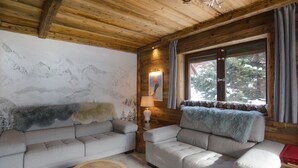 A cozy cabin interior with two sofas, a round wooden table, a lamp, and a window with curtains. - Apartment chalet vallée d'incles Andorra (Canillo)