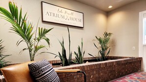 A modern atrium with a brick wall, a framed sign above, and various plants.