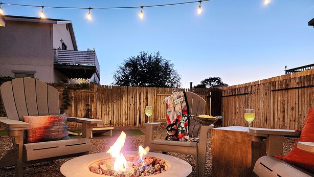 An outdoor seating area with a fire pit, chairs, and tables.