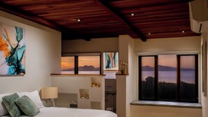 Une chambre avec un grand lit, une fenêtre donnant sur les montagnes et des œuvres d’art abstrait accrochées aux murs.