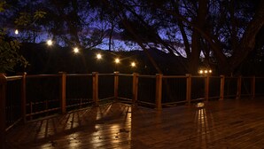 A wooden deck with string lights and a wooden railing. - Cabañas La Laguna Lodge (Corralillo)