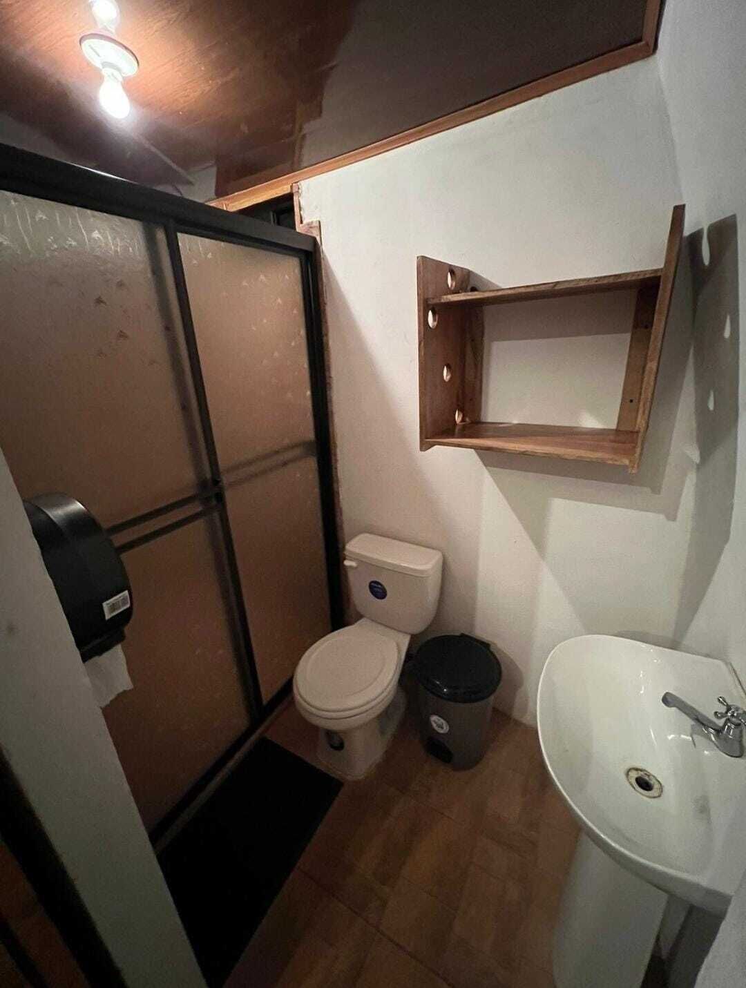 Une petite salle de bain comprenant des toilettes, un lavabo et une petite étagère au-dessus du lavabo.