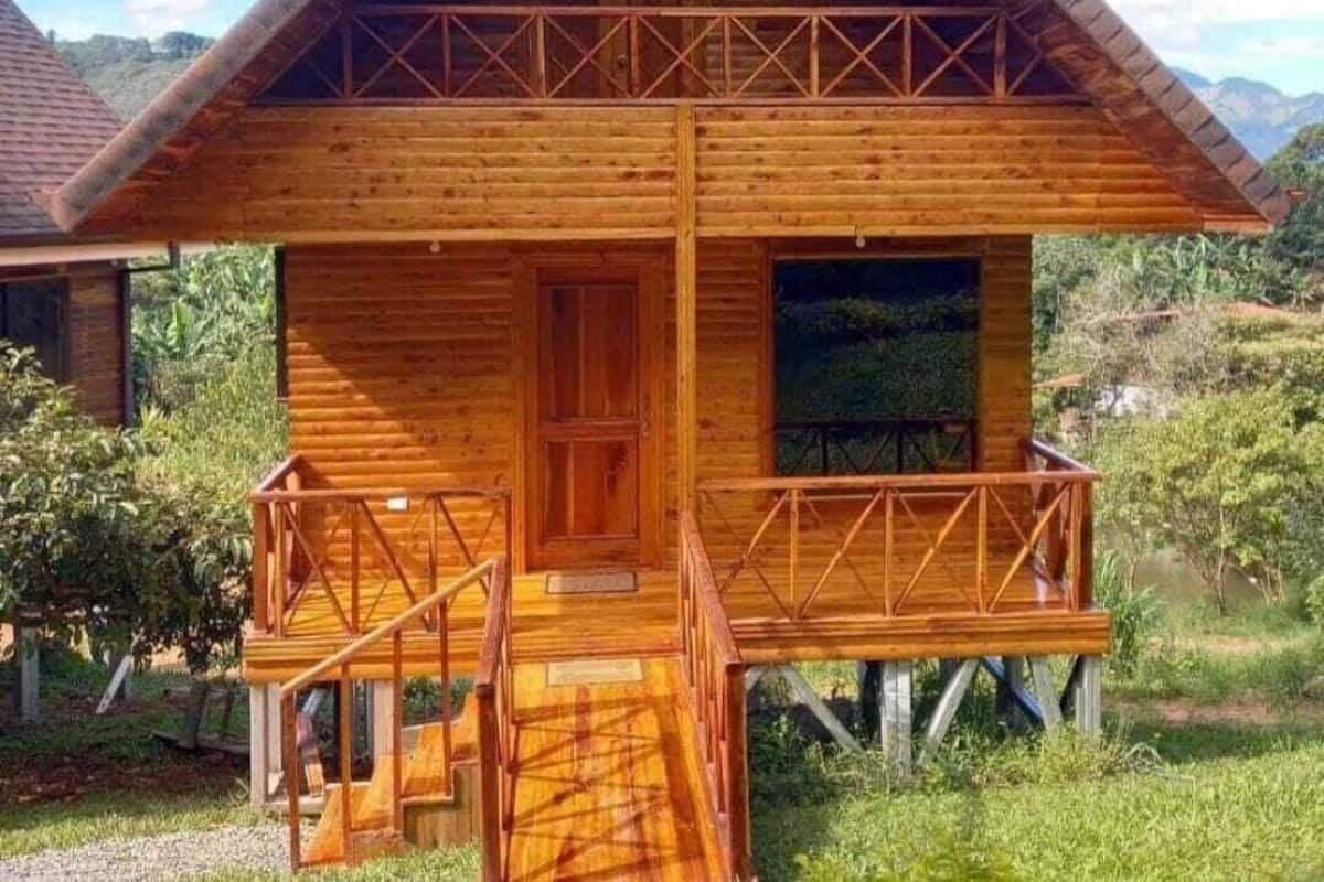 Une cabane en bois dotée d’un balcon, d’une porte d’entrée et d’une fenêtre.