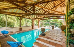 An indoor swimming pool with a wooden ceiling and large windows.