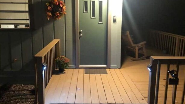 Eine Holzterrasse mit einer Tür, einer kleinen Veranda und einem Geländer.