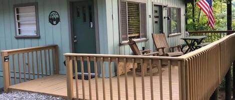 Una piccola baita blu chiaro con un portico in legno e due sedie.