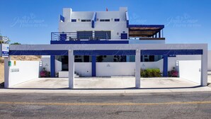 A modern hotel with a two-story structure, a covered parking area, and a sign indicating availability.