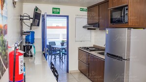 A kitchen with a stainless steel refrigerator, a microwave, and a stove. There is a fire extinguisher and a water dispenser on the wall.