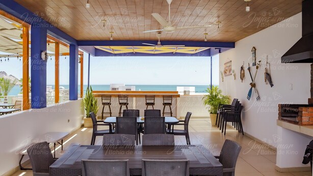 A terrace with a dining area, ceiling fans, and a view of the sea.