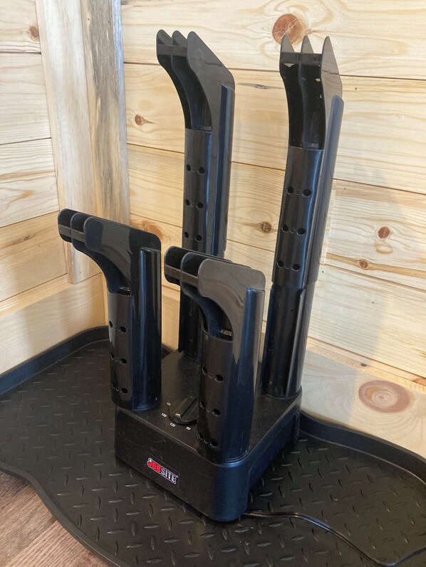 A black knife block with three knives on a black mat against a wooden wall.