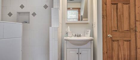 Een badkamer met witte tegels, een houten deur en een wastafel met toiletartikelen.