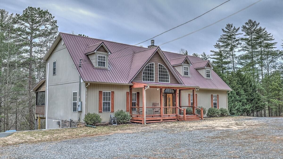 A two-story house with a porch, a garage, and a gravel driveway.