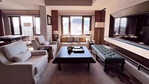 Un salon moderne avec un canapé, des fauteuils, une table basse et un téléviseur.