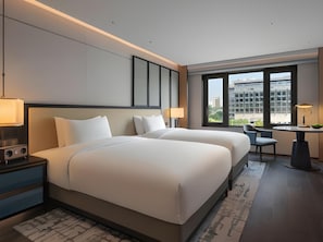 A hotel room with two beds, a desk, and a view of the city. - Prime (Beijing)